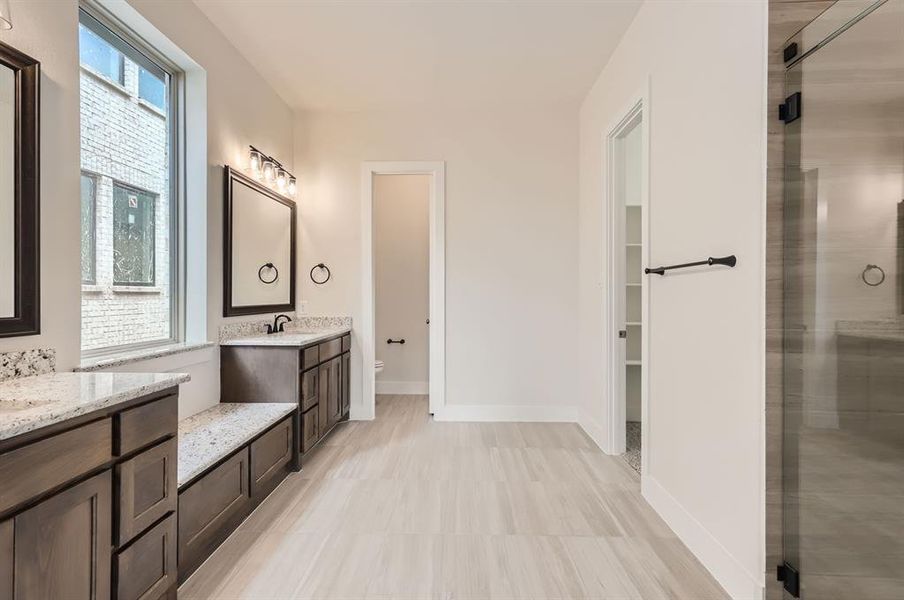 Bathroom featuring a shower with shower door, vanity, and toilet