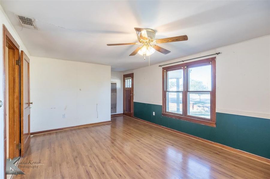 Empty room with wood finished floors and a ceiling fan Empty room with wood finished floors and a ceiling fan