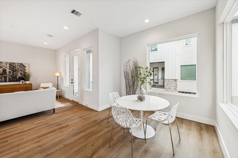 This bright dining space is filled with natural light streaming through two large picture windows—perfect for memorable meals.