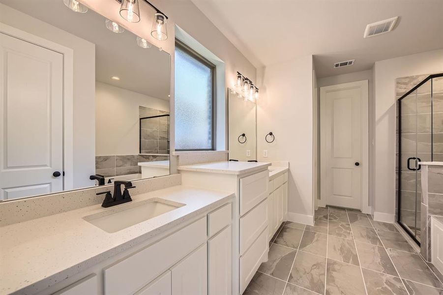 Full bathroom with a shower stall, two vanities, and marble look tiles Full bathroom with a shower stall, two vanities, and marble look tiles