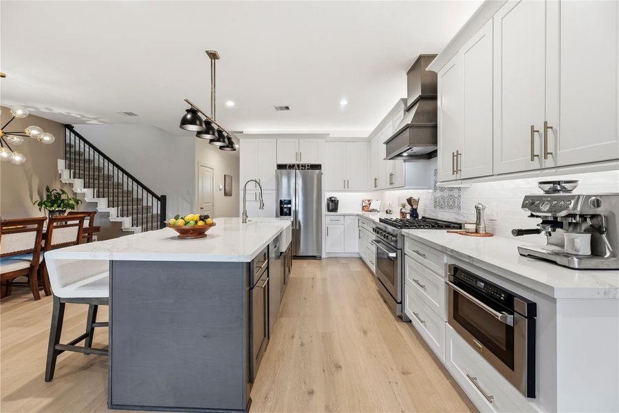 Kitchen with quartz countertops, hardwood cabinetry, a built-in ZLINE microwave drawer and stainless steel appliances.