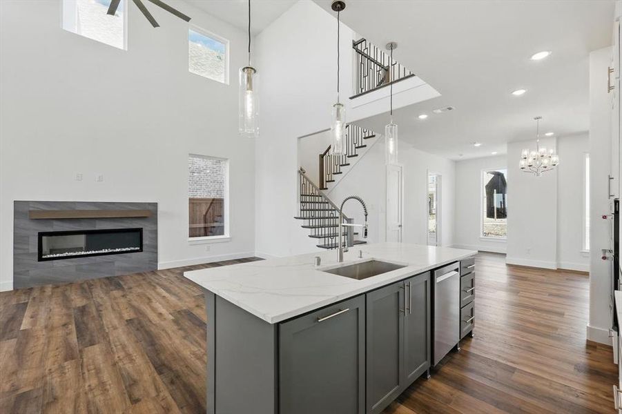 Kitchen featuring an island with sink, open floor plan, a sink, and gray cabinetry