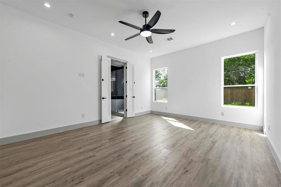 Unfurnished bedroom with a spacious closet, ceiling fan, and hardwood / wood-style floors