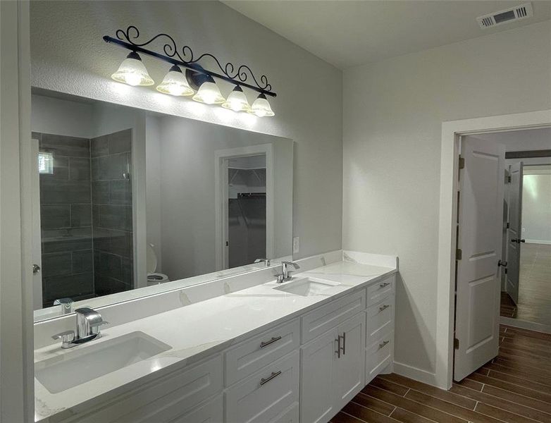 Bathroom with vanity, a tile shower, and toilet