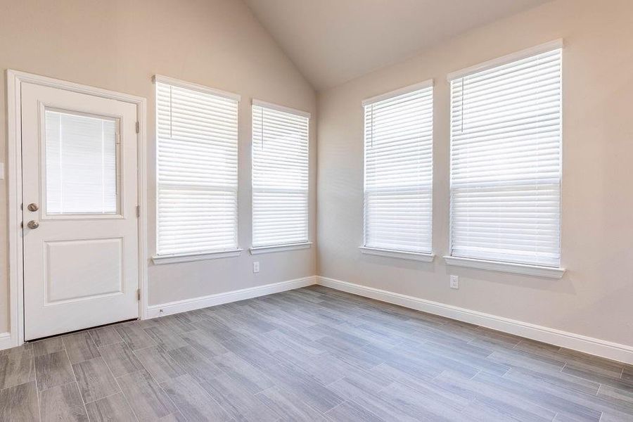 Unfurnished room featuring light wood-style floors and vaulted ceiling Unfurnished room featuring light wood-style floors and vaulted ceiling