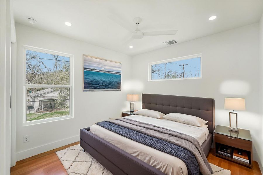 Bedroom with multiple windows, wood finished floors, recessed lighting, ceiling fan, and baseboards
