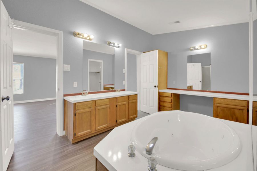 Full bathroom featuring vanity, a whirlpool tub, and light wood-style floors