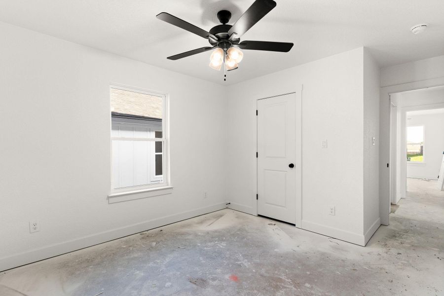 Unfurnished bedroom with concrete flooring and a ceiling fan Unfurnished bedroom with concrete flooring and a ceiling fan
