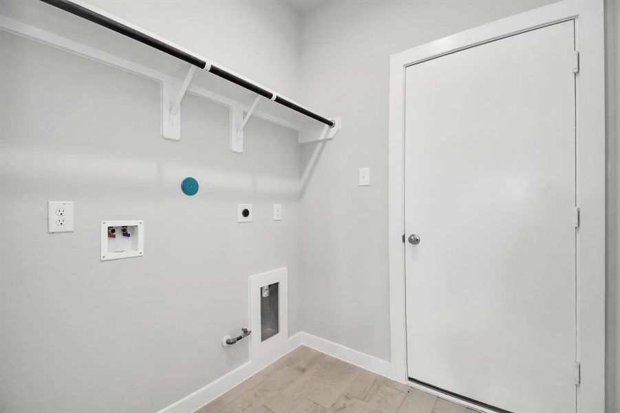 Located on first floor, a stylish laundry room where practicality meets a contemporary aesthetic. The dark finishes lend a sophisticated touch, creating a space that is both functional and visually appealing. Both electric and gas connections available. Sample photo of completed home. Actual colors and selections may vary.