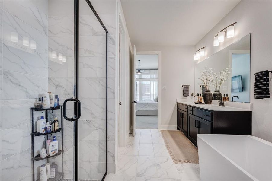 Ensuite bathroom featuring a freestanding tub, double vanity, light marble finish floors, and a marble finish shower