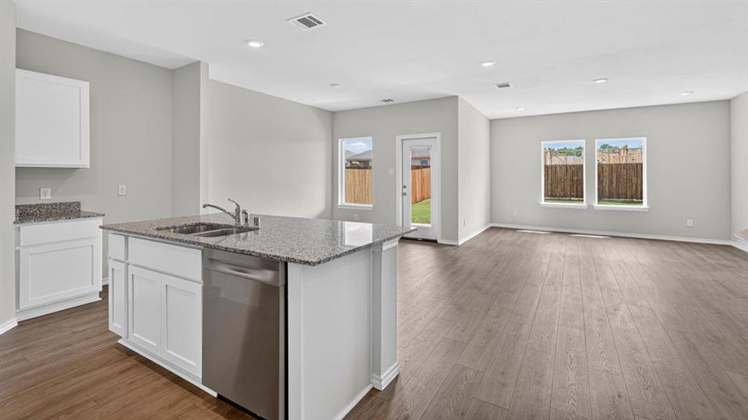 Open-concept living space featuring wood-finish flooring, recessed lighting, and light gray wall paint Open-concept living space featuring wood-finish flooring, recessed lighting, and light gray wall paint