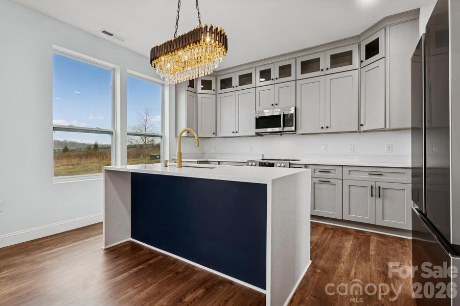 gorgeous kitchen area provides all of the stainless appliances needed for everyday cooking, large counter spacing, stacked cabinetry, elegant lighting and a waterfall quartz counter top island