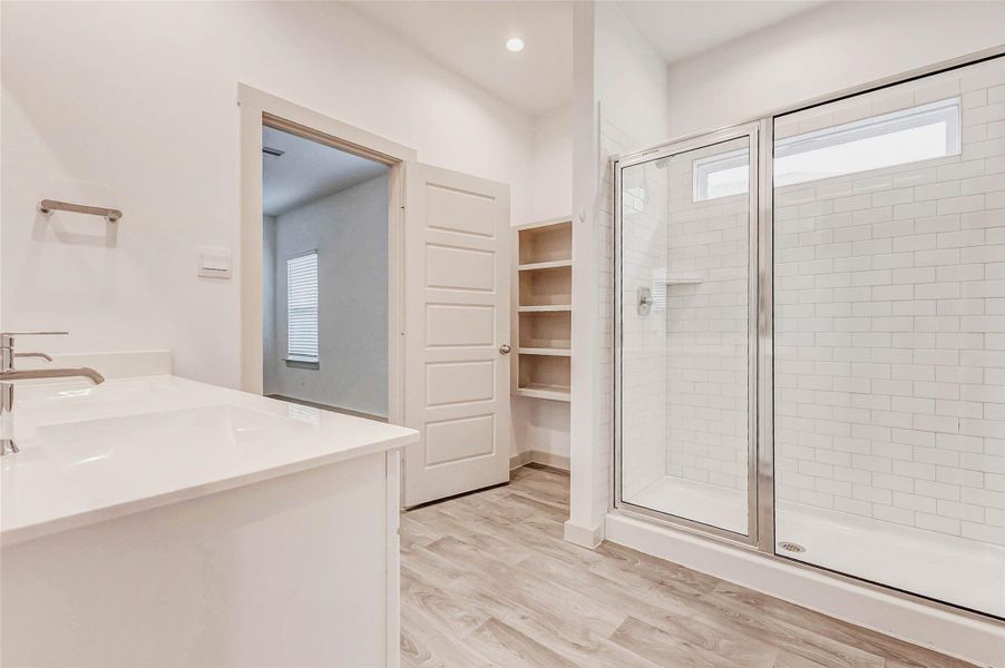 Pristine and practical, the primary bath includes a large glass shower with a built-in shelf, tall ceilings with recessed lighting, and open shelving for linens and bath essentials, all just steps from the bedroom for added comfort and privacy. Pristine and practical, the primary bath includes a large glass shower with a built-in shelf, tall ceilings with recessed lighting, and open shelving for linens and bath essentials, all just steps from the bedroom for added comfort and privacy.