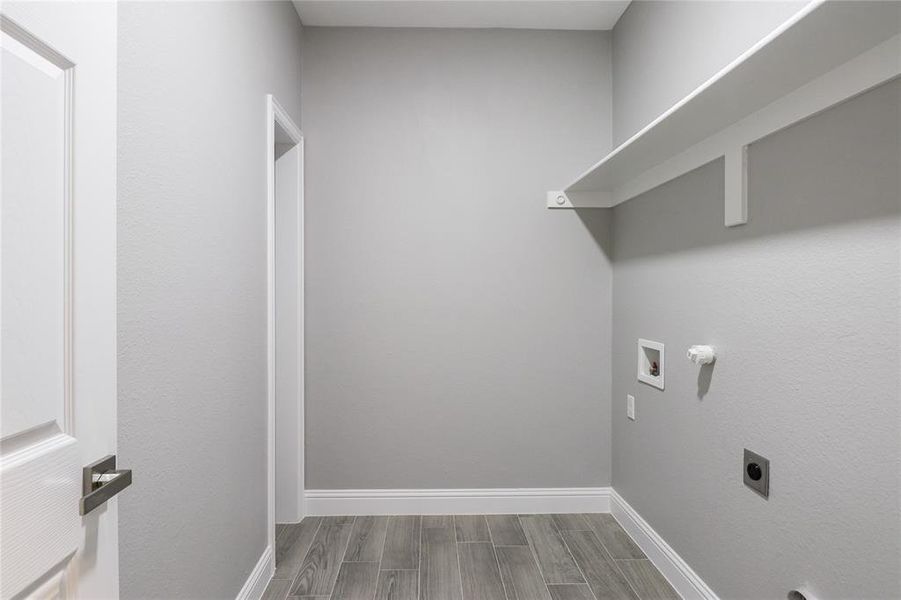 Clothes washing area with wood-type flooring, electric dryer hookup, and washer hookup