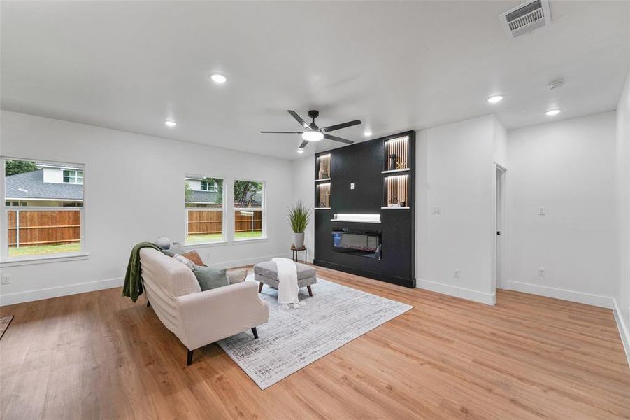 Spacious living area featuring wood-finish flooring, recessed lighting, and a modern ceiling fan Spacious living area featuring wood-finish flooring, recessed lighting, and a modern ceiling fan