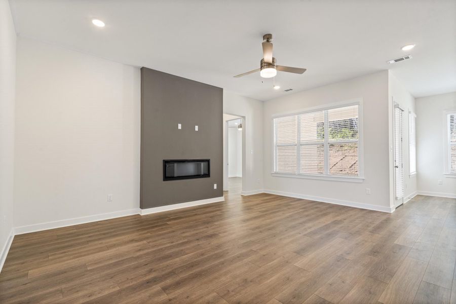 Unfurnished living room with ceiling fan, dark wood-style floors, a glass covered fireplace, and recessed lighting