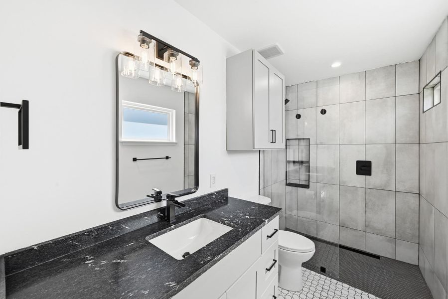 Bathroom with vanity, a tile shower, and light tile patterned flooring