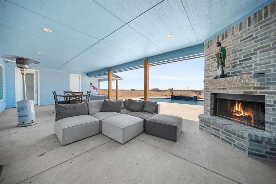 View of patio / terrace featuring an outdoor brick fireplace, outdoor lounge area, and an outdoor pool