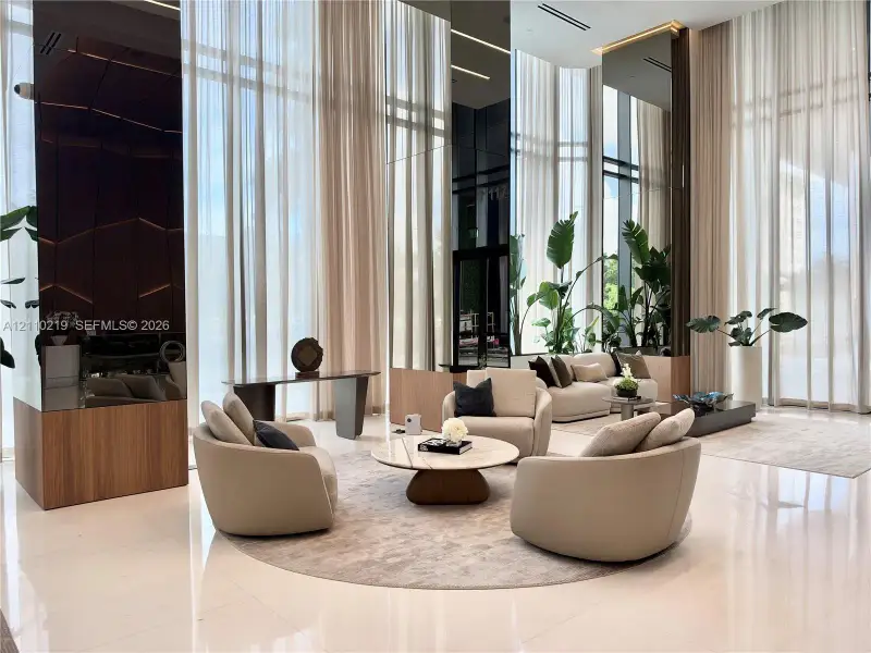 Double-height floor-to-ceiling windows, polished stone flooring, integrated linear lighting, mirrored wall accents, and wood-finish paneling