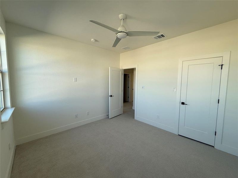 secondary bedroom with ceiling fan and light carpet