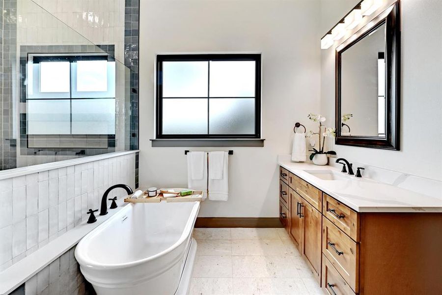 Bathroom featuring a freestanding bath, vanity, light tile patterned floors, and tiled shower