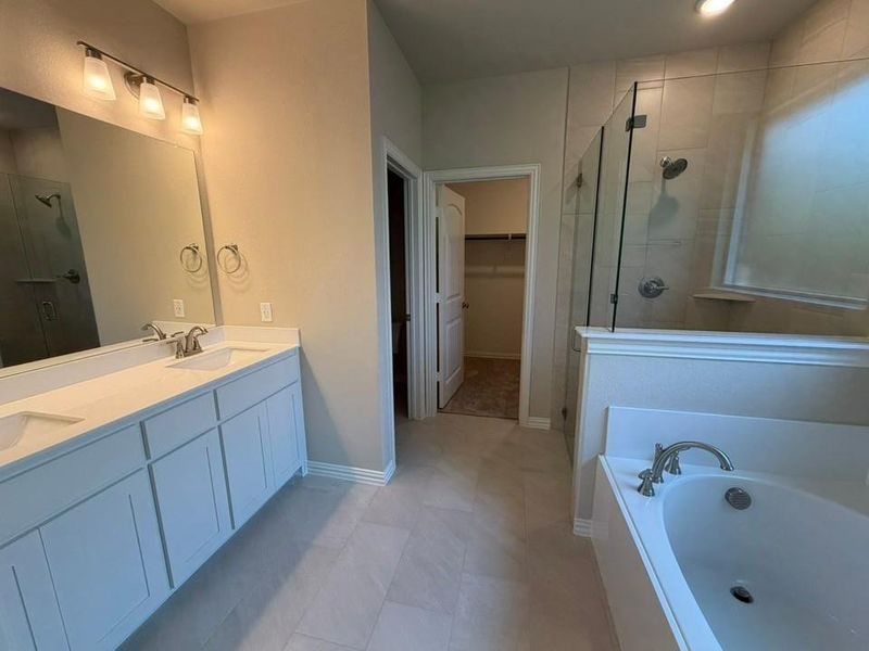Bathroom featuring light-toned tile flooring and a double vanity with white cabinetry