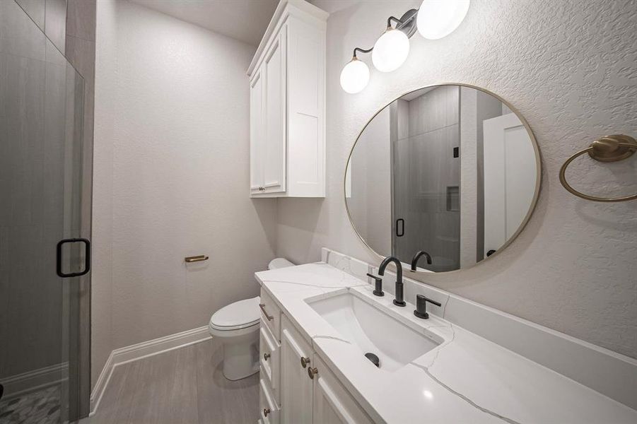 Bathroom featuring vanity, a stall shower, and a textured wall Bathroom featuring vanity, a stall shower, and a textured wall