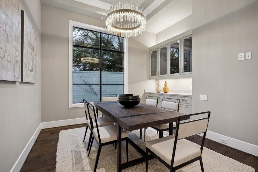 Enjoy relaxed dining in the stylishly appointed breakfast room, featuring custom built-in cabinetry, a sleek serving countertop, and ample storage. A contemporary light fixture, elegant tray ceiling, and expansive window with serene treetop views complete the space.