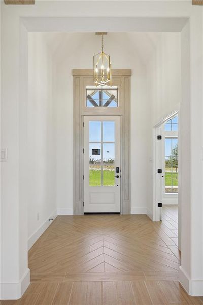 Foyer entrance featuring a wealth of natural light, light parquet floors, and a notable chandelier