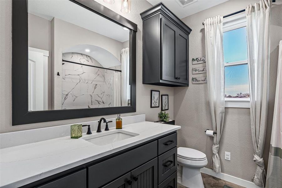 Full bathroom with a shower with curtain, vanity, and a textured wall Full bathroom with a shower with curtain, vanity, and a textured wall