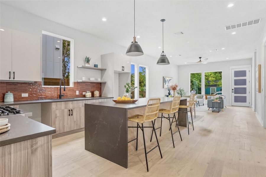 Kitchen with open shelves, a kitchen island, recessed lighting, a kitchen breakfast bar, and light wood finished floors Kitchen with open shelves, a kitchen island, recessed lighting, a kitchen breakfast bar, and light wood finished floors