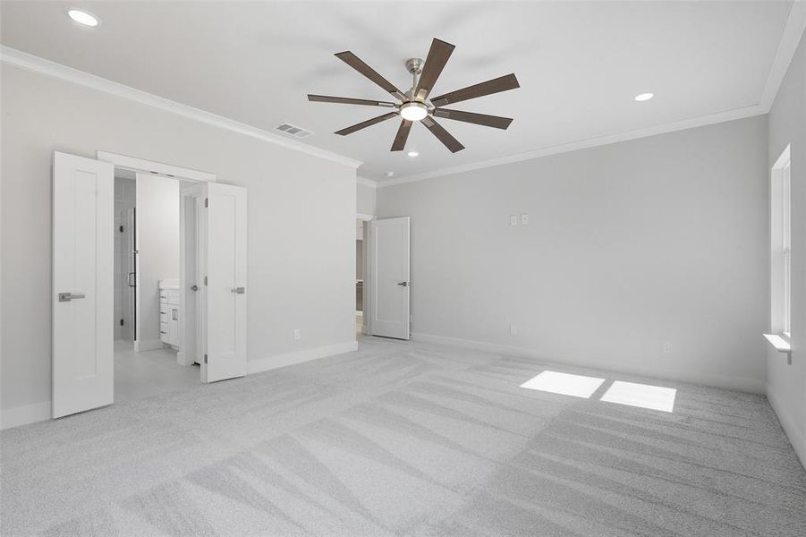 Unfurnished bedroom with ornamental molding, light colored carpet, recessed lighting, ceiling fan, and ensuite bath Unfurnished bedroom with ornamental molding, light colored carpet, recessed lighting, ceiling fan, and ensuite bath