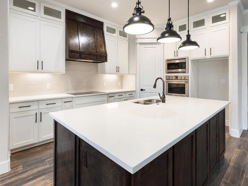 Kitchen featuring a kitchen island with sink, stainless steel appliances, sink, and white cabinetry