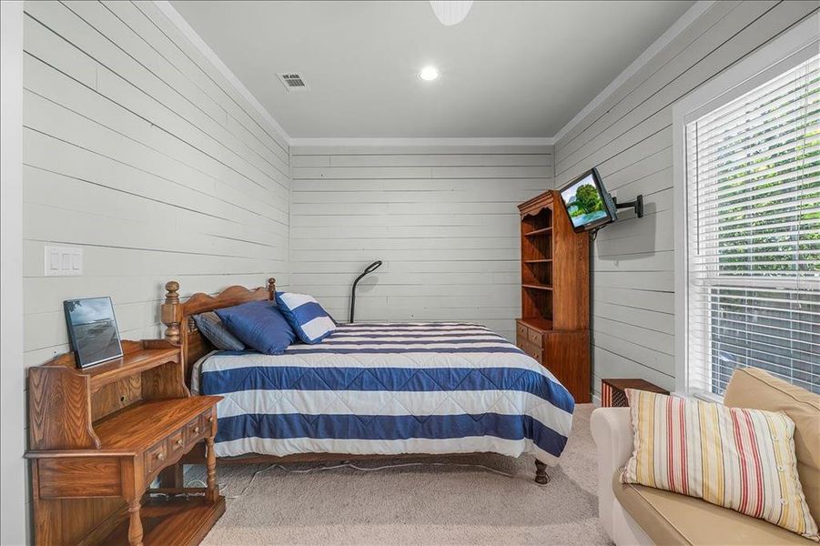 Carpeted bedroom featuring crown molding and wooden walls