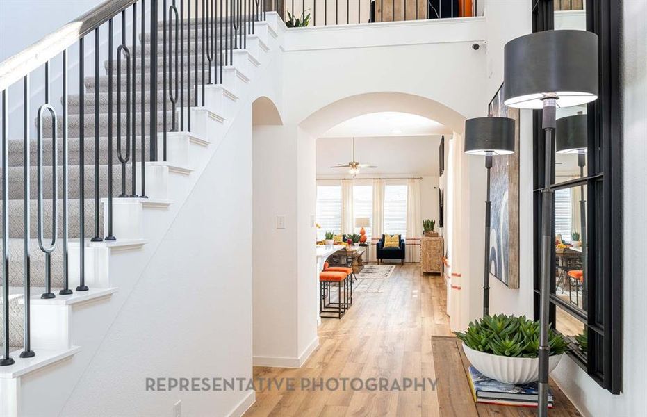 Entryway featuring arched walkways, light wood-style flooring, and stairs