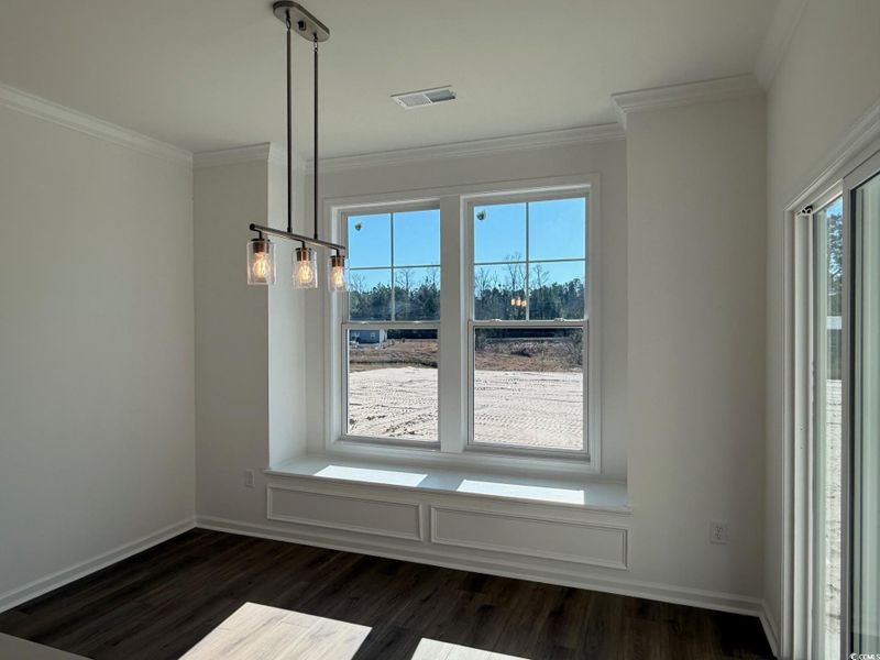 Unfurnished dining area featuring crown molding and dark wood-style flooring