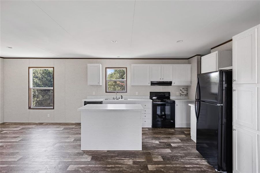 Kitchen with white cabinets, dark hardwood / wood-style flooring, black appliances, and a center island