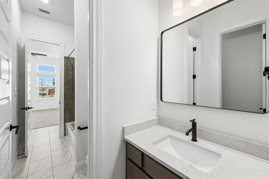 Bathroom vanity with a rectangular undermount sink, light-toned countertop, and matte black faucet