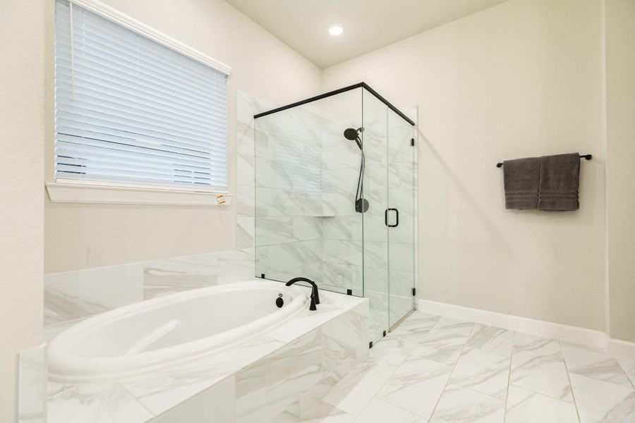 The primary bathroom has beautiful tile floors and a window for natural light.
