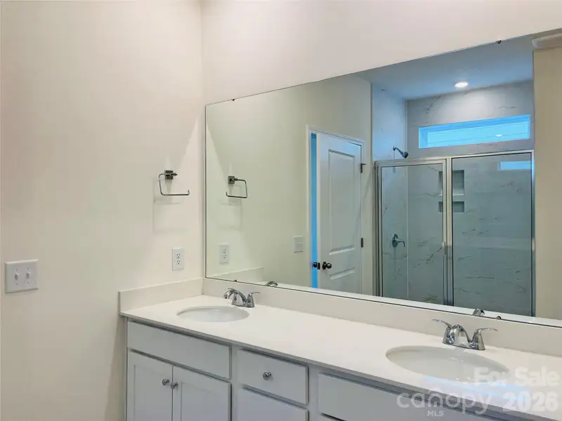 Primary bath with dual vanity, quartz counters, tiled shower.