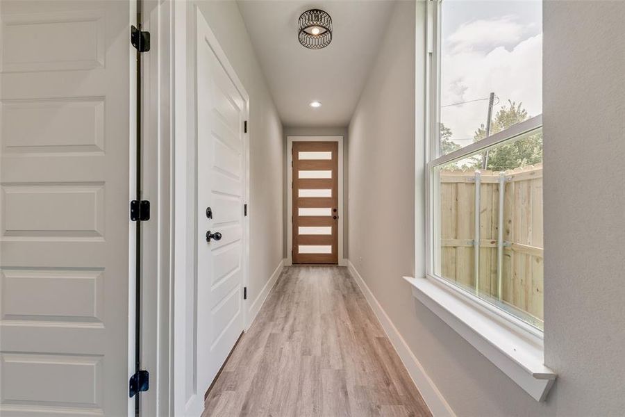 Doorway to outside with light wood LVP and recessed lighting Doorway to outside with light wood LVP and recessed lighting