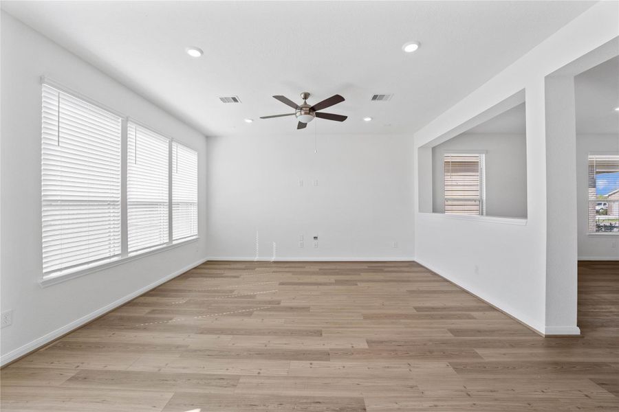 Relax and unwind in this cozy family room, featuring high ceilings, ceiling fan with lighting, recessed lighting, and a wall of large windows with privacy blinds that provides natural light. Relax and unwind in this cozy family room, featuring high ceilings, ceiling fan with lighting, recessed lighting, and a wall of large windows with privacy blinds that provides natural light.