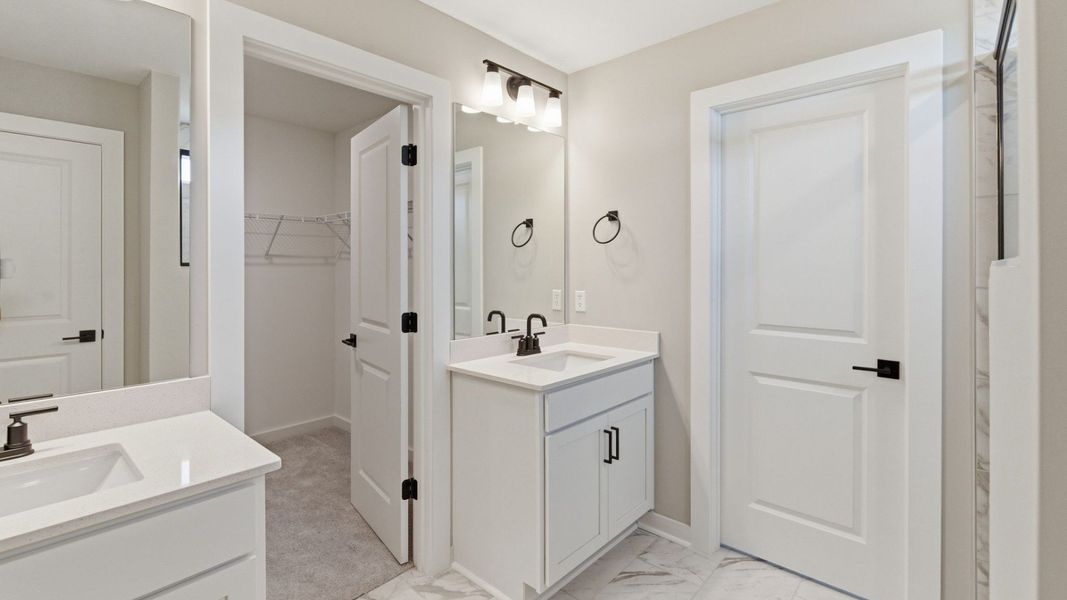 Bathroom with dual vanity and access to closet