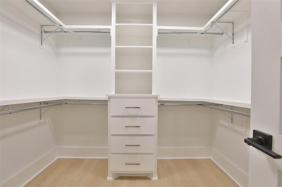 Spacious walk-in closet with custom shoe storage and sleek built-in cabinetry.