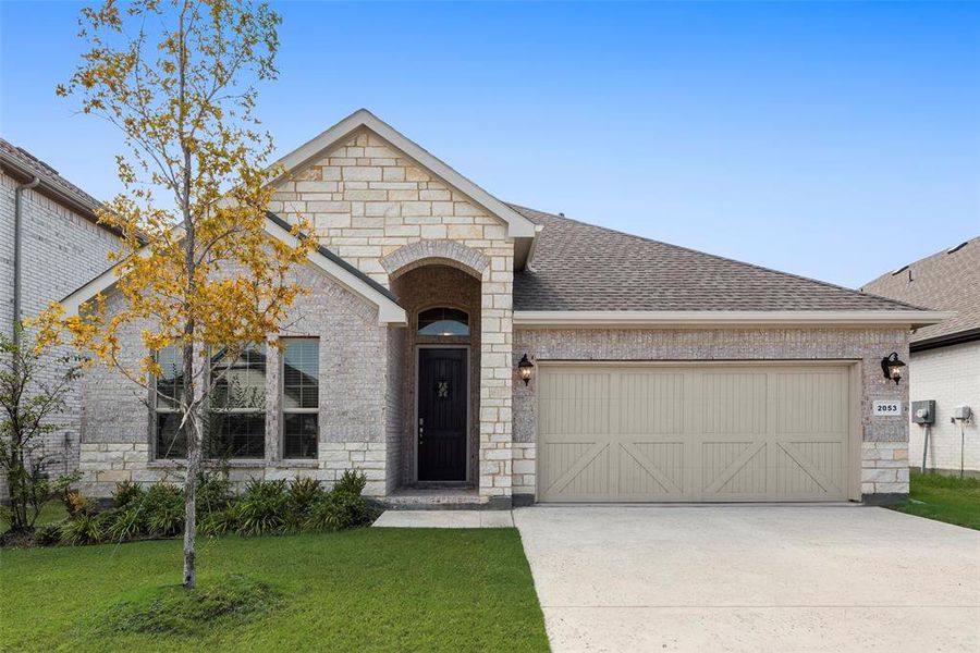 French provincial home featuring stone siding, brick siding, concrete driveway, and a shingled roof
