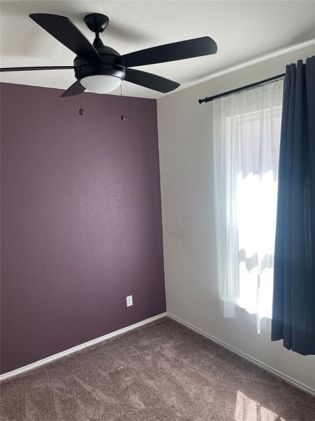 Carpeted empty room with ceiling fan and a textured wall Carpeted empty room with ceiling fan and a textured wall