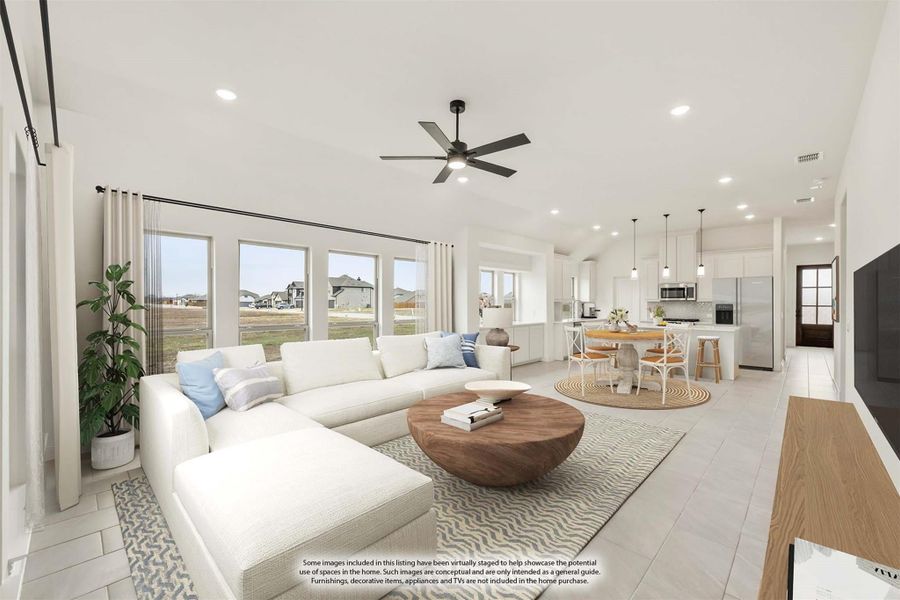 Open-concept living room with white sectional sofa, ceiling fan, and kitchen visible in background