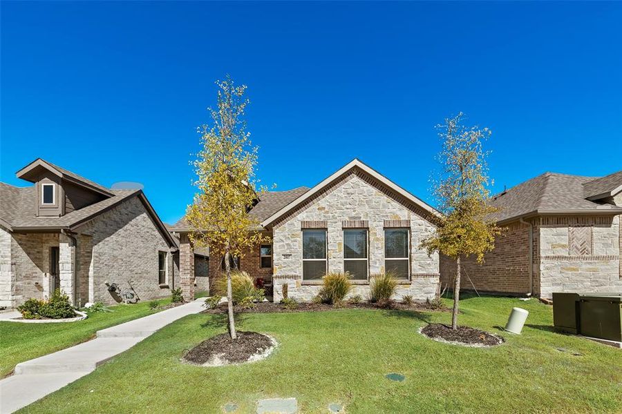 View of front facade featuring a front yard, stone siding, and brick siding View of front facade featuring a front yard, stone siding, and brick siding