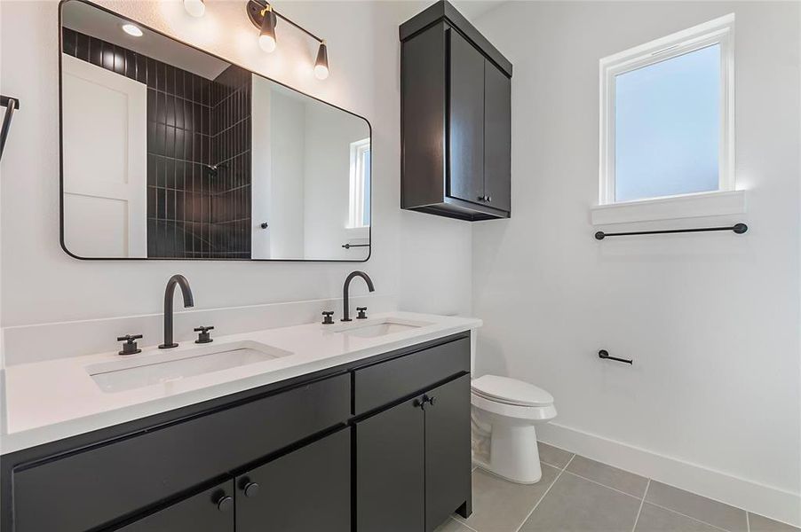 Double vanity with white countertops, matte black faucets, and dark cabinetry Double vanity with white countertops, matte black faucets, and dark cabinetry