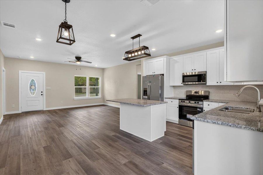 Plank flooring runs throughout this open space connecting a modern kitchen to the main living area. Plank flooring runs throughout this open space connecting a modern kitchen to the main living area.